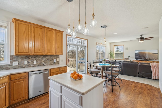 kitchen with tasteful backsplash, dishwasher, wood finished floors, and light countertops