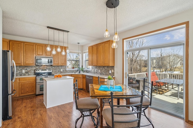 kitchen with light countertops, a center island, appliances with stainless steel finishes, and a sink