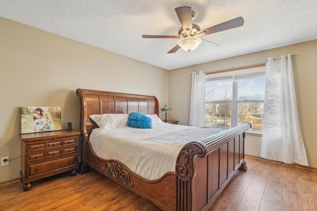 bedroom with a textured ceiling, ceiling fan, and wood-type flooring