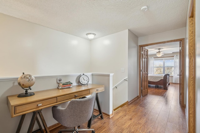 home office with baseboards, wood-type flooring, and a textured ceiling