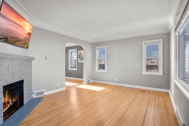 unfurnished living room featuring ornamental molding, a fireplace, and light hardwood / wood-style flooring