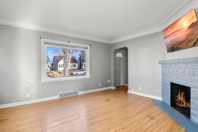 unfurnished living room with light wood-type flooring, a brick fireplace, and crown molding