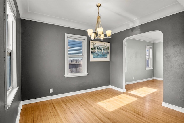 empty room featuring hardwood / wood-style flooring, crown molding, and a notable chandelier