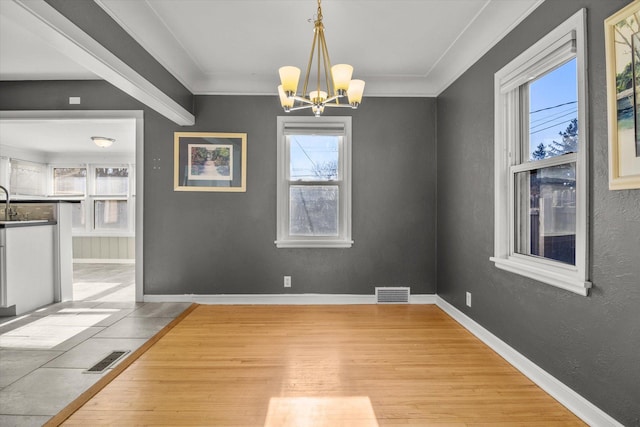 unfurnished dining area featuring ornamental molding, light wood-type flooring, and an inviting chandelier