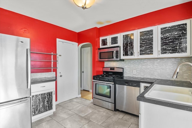 kitchen with sink, light tile patterned floors, appliances with stainless steel finishes, tasteful backsplash, and white cabinetry