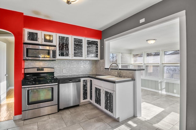 kitchen with backsplash, sink, appliances with stainless steel finishes, white cabinetry, and kitchen peninsula