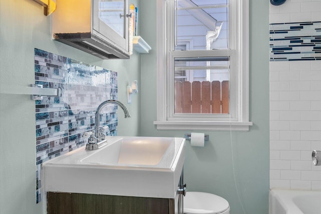 bathroom featuring vanity, toilet, and backsplash