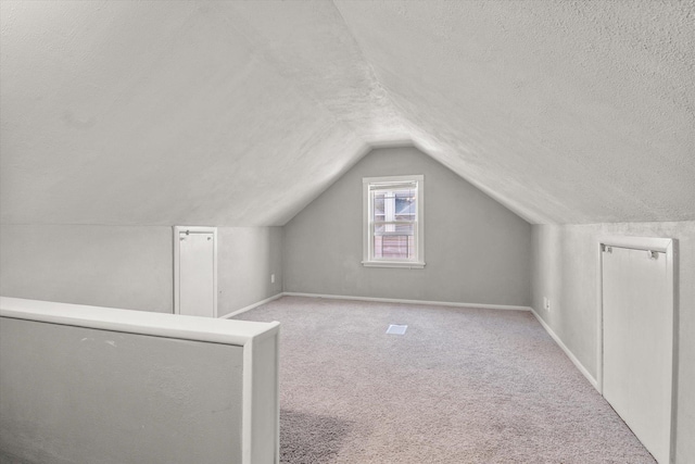 bonus room featuring light carpet, a textured ceiling, and lofted ceiling