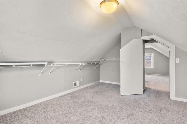 spacious closet featuring light colored carpet and lofted ceiling