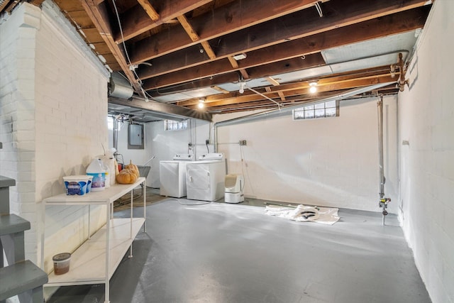 basement with electric panel and washing machine and clothes dryer