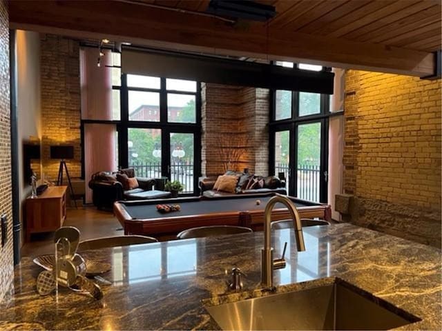 recreation room featuring wood ceiling, brick wall, a towering ceiling, billiards, and sink