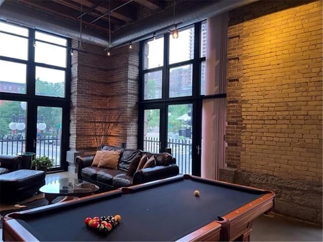 recreation room featuring brick wall, a towering ceiling, and billiards