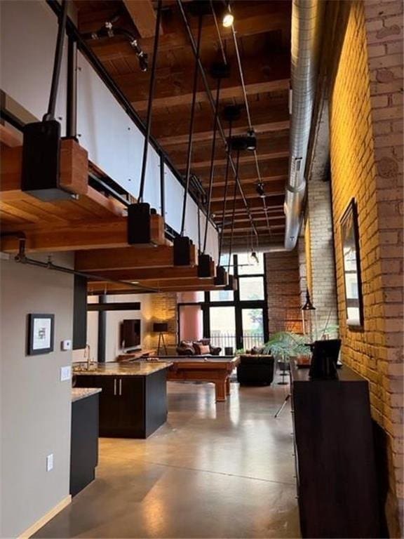 kitchen with brick wall, a high ceiling, dark brown cabinetry, and billiards