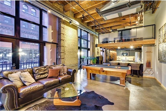 game room with billiards, wood ceiling, concrete floors, a towering ceiling, and brick wall