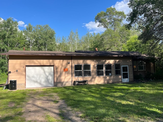 back of property with central AC, a garage, and a lawn