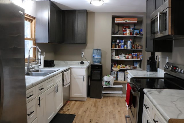 kitchen featuring white cabinets, sink, light hardwood / wood-style flooring, light stone counters, and stainless steel appliances