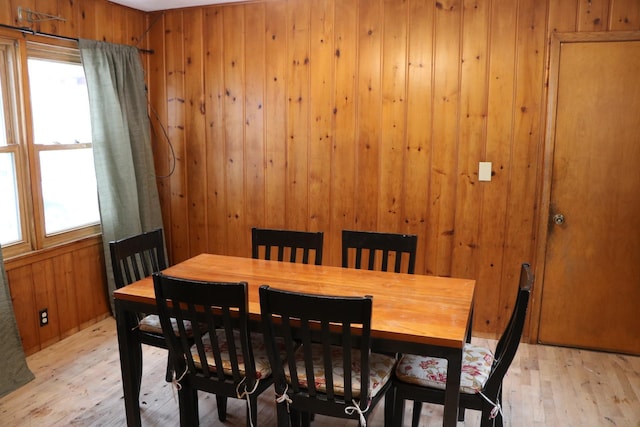 dining space with light hardwood / wood-style floors and wood walls