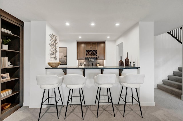 kitchen featuring tasteful backsplash, a breakfast bar area, and light colored carpet