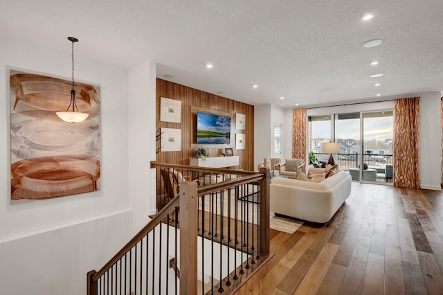 living room with hardwood / wood-style floors, expansive windows, wood walls, and a textured ceiling