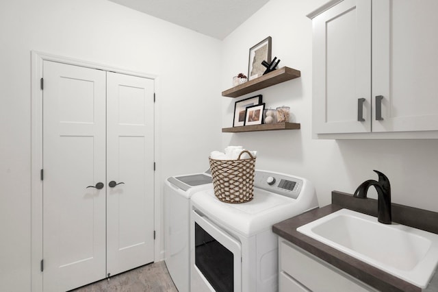 clothes washing area with cabinets, independent washer and dryer, sink, and light hardwood / wood-style flooring