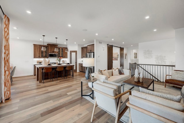 living room with a barn door and light wood-type flooring