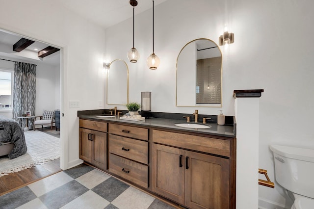 bathroom featuring vanity, beam ceiling, and toilet