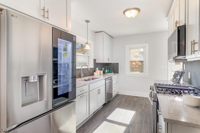 kitchen featuring white cabinetry, sink, stainless steel appliances, backsplash, and decorative light fixtures