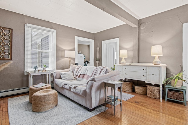 living room with baseboard heating, light hardwood / wood-style flooring, and beam ceiling