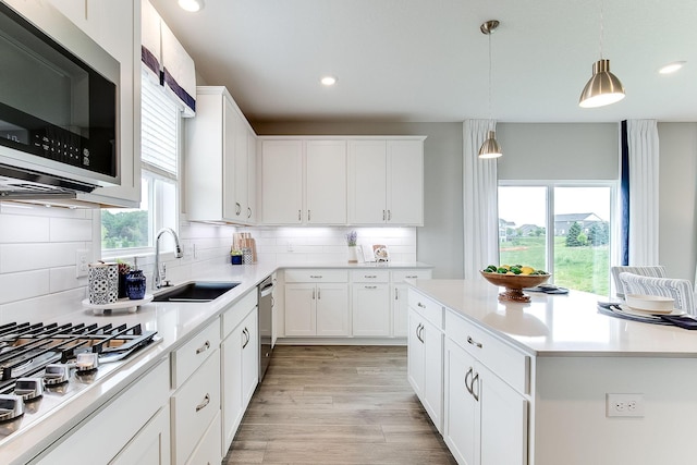 kitchen featuring decorative backsplash, stainless steel appliances, white cabinetry, and sink