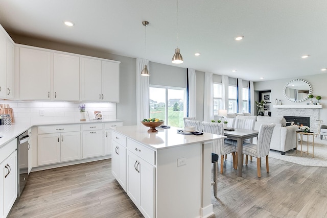 kitchen featuring stainless steel dishwasher, decorative backsplash, a kitchen island, and white cabinetry