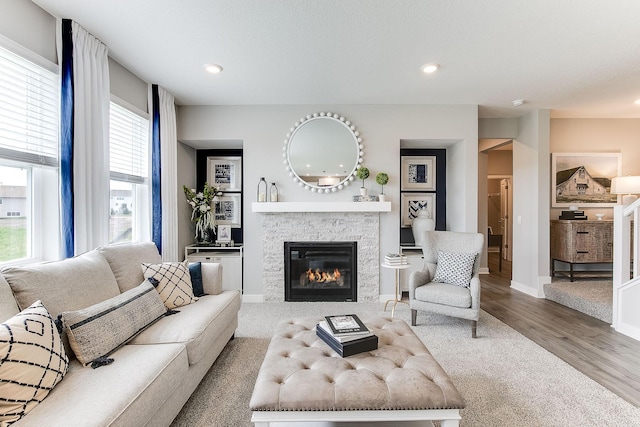 living room featuring a stone fireplace, plenty of natural light, and hardwood / wood-style floors