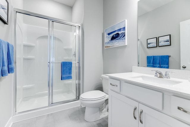 bathroom featuring tile patterned flooring, vanity, toilet, and a shower with door