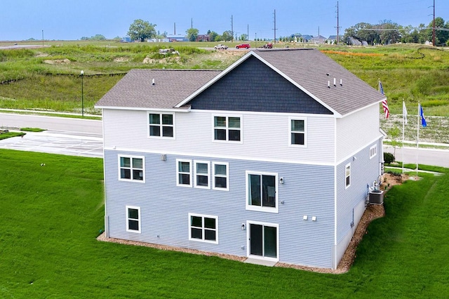 rear view of property with central AC and a yard