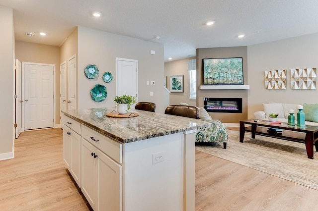 kitchen featuring white cabinets, light stone counters, light hardwood / wood-style flooring, and a kitchen island