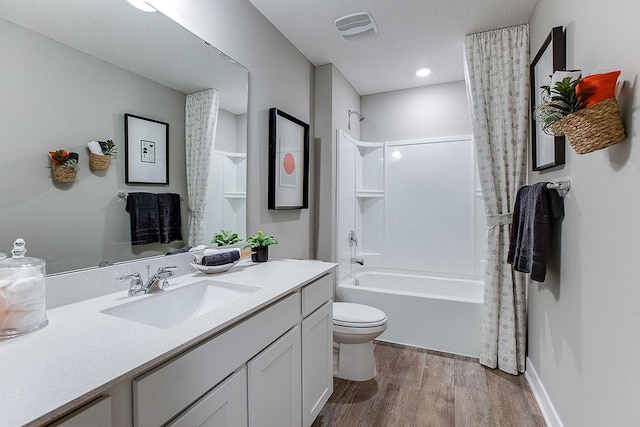 full bathroom featuring hardwood / wood-style floors, shower / bath combo, vanity, toilet, and a textured ceiling