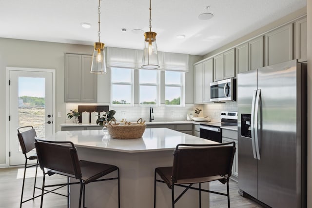 kitchen featuring a center island, stainless steel appliances, tasteful backsplash, pendant lighting, and gray cabinets