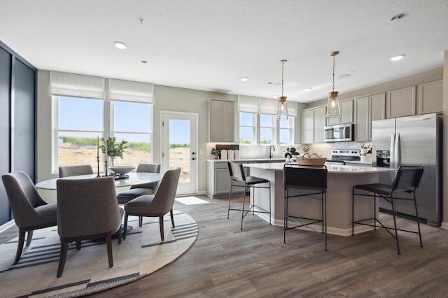 kitchen featuring gray cabinetry, stainless steel appliances, pendant lighting, hardwood / wood-style flooring, and a kitchen island