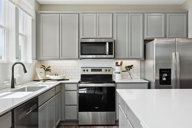 kitchen featuring tasteful backsplash, gray cabinetry, sink, and stainless steel appliances