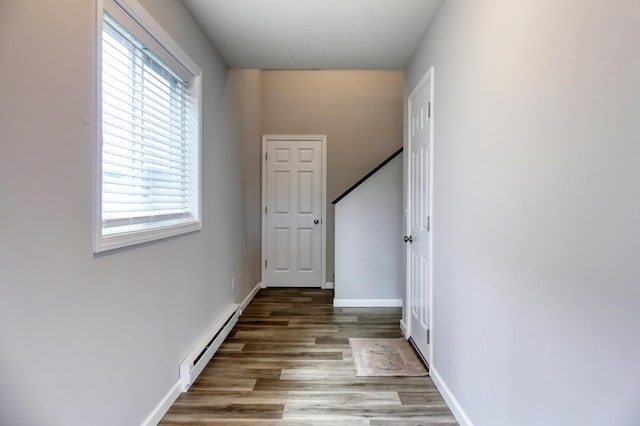 hall with wood-type flooring and baseboard heating