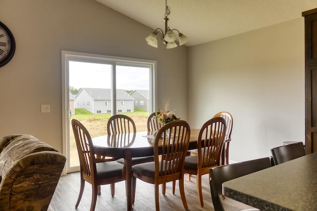 dining space with light hardwood / wood-style flooring, a chandelier, and lofted ceiling