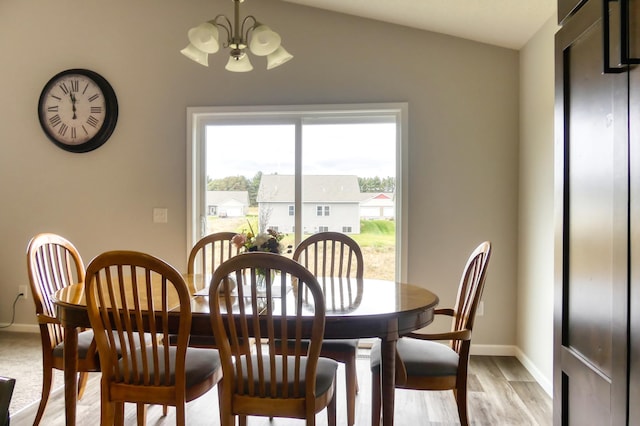 dining area with light hardwood / wood-style flooring, vaulted ceiling, and a notable chandelier