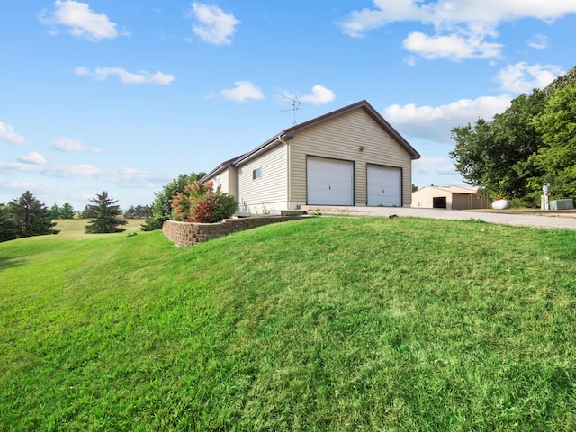 view of side of property featuring a garage, a yard, and an outbuilding