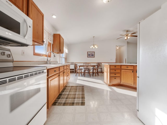 kitchen featuring ceiling fan with notable chandelier, white appliances, vaulted ceiling, sink, and pendant lighting