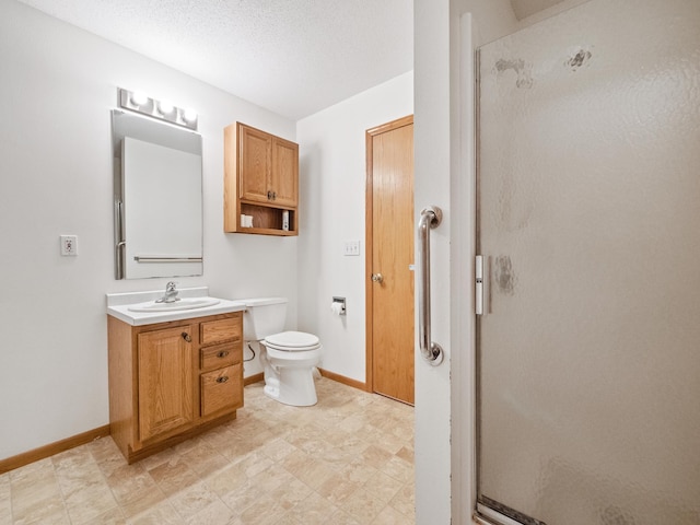 bathroom with a textured ceiling, vanity, toilet, and walk in shower