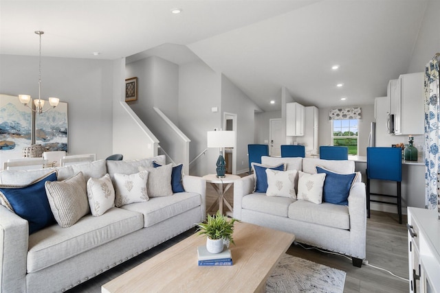 living room with wood-type flooring, lofted ceiling, and an inviting chandelier