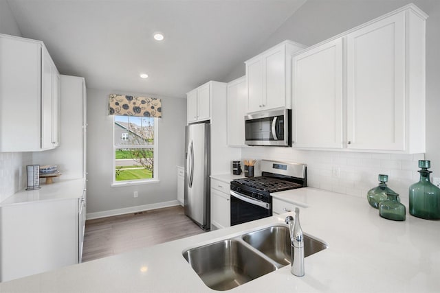 kitchen with backsplash, sink, white cabinets, and appliances with stainless steel finishes