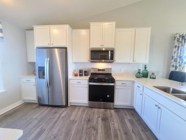 kitchen with white cabinets, sink, lofted ceiling, and stainless steel appliances