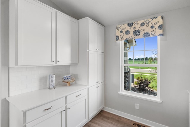 interior space with a healthy amount of sunlight, wood-type flooring, and white cabinetry