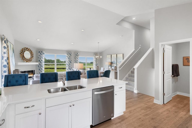 kitchen with dishwasher, white cabinets, sink, hanging light fixtures, and light wood-type flooring