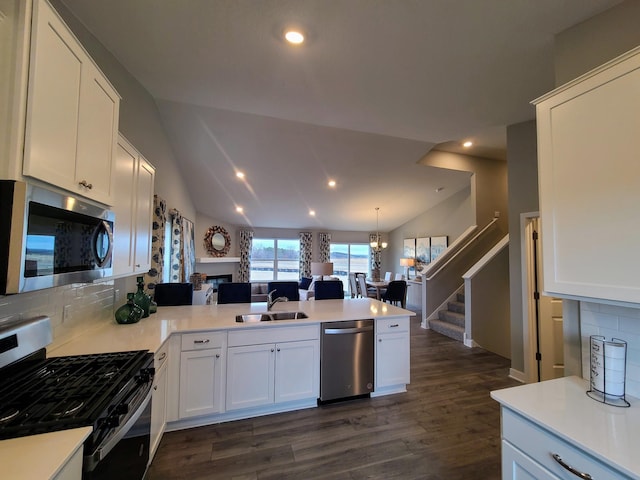 kitchen featuring backsplash, white cabinets, vaulted ceiling, and appliances with stainless steel finishes